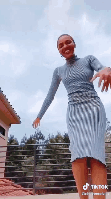 a woman in a blue dress is dancing on a balcony with tiktok written on the bottom of the screen