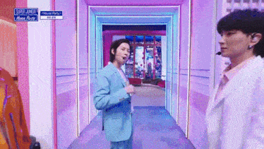 a man in a blue suit and a man in a white suit are standing in a hallway .