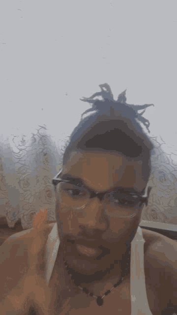 a young man wearing glasses and a necklace