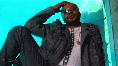 a man wearing sunglasses and a necklace has the letter v on his head