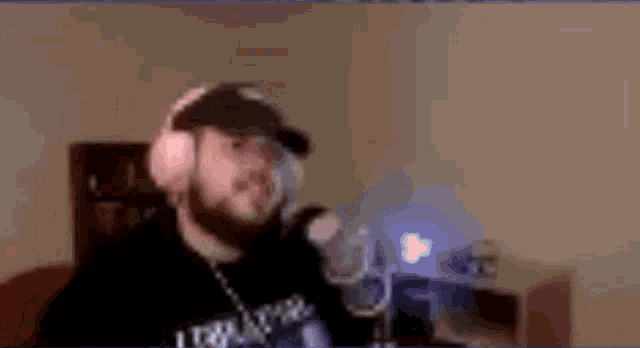 a man wearing headphones and a hat is dancing in front of a computer screen .