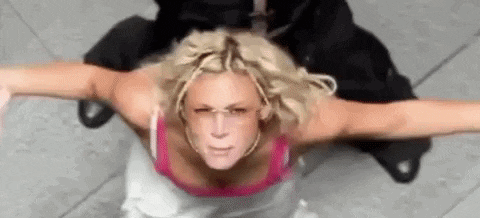 a woman is sitting on the ground with her arms outstretched while a man sits behind her .