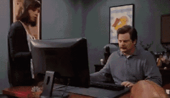 a man is sitting at a desk with a computer and a woman is standing behind him .