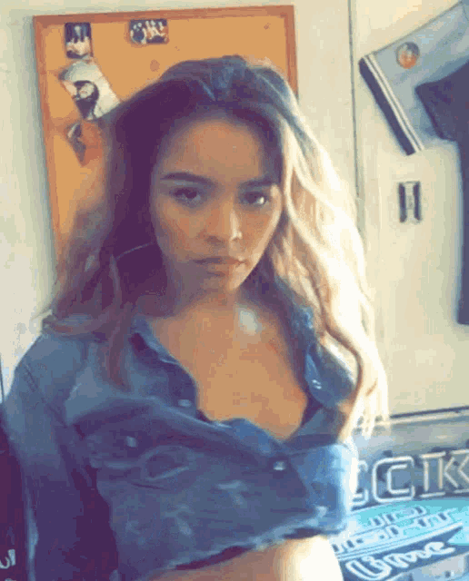 a woman in a denim shirt is standing in front of a sign that says ck on it