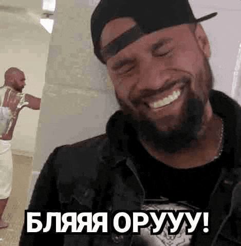 a man with a beard wearing a hat is smiling .