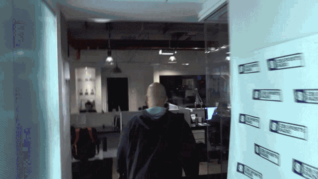 a man walks through a hallway with a sign on the wall that says ' cbs community radio ' on it