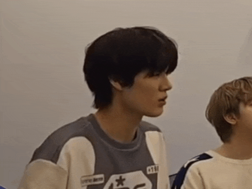a boy with short hair is making a funny face while another boy looks on .