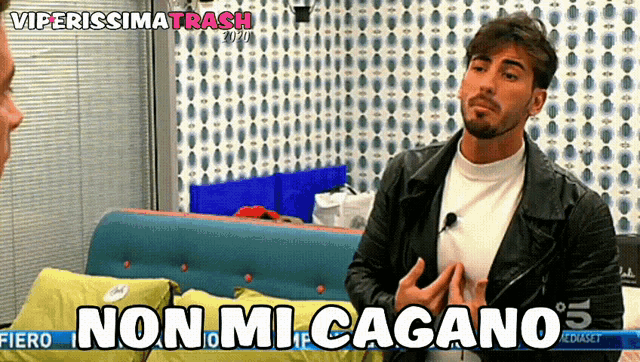a man sitting on a couch with the words non mi cagano on the screen behind him