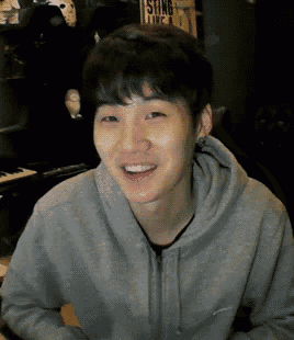 a young man wearing a grey hoodie is smiling