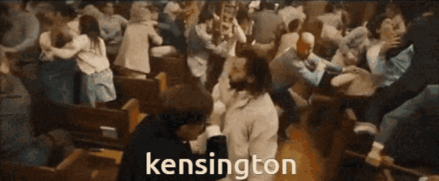 a crowd of people are gathered in a church and the word kensington is visible