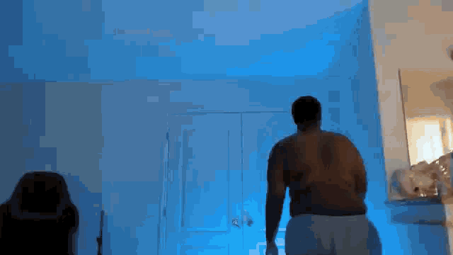 a shirtless man is standing in front of a blue sky