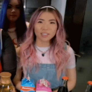 a woman with pink hair is holding a carton of milk and a bottle of juice .