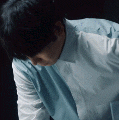 a man wearing a white shirt and a blue vest looks down
