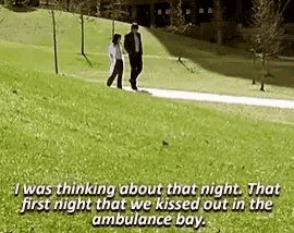 a man and a woman are walking down a path in a park and talking .