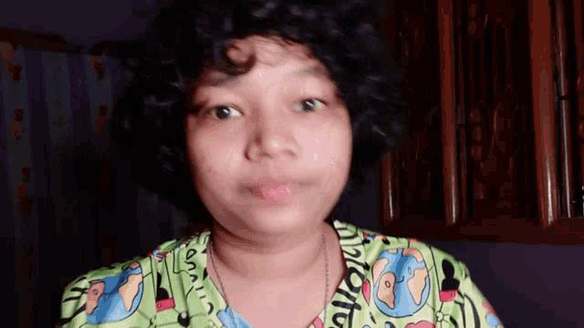 a woman with curly hair is wearing a green shirt that says ' i love you ' on the front