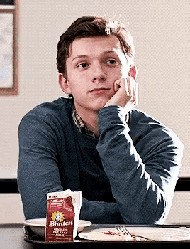a young man sitting at a table with a carton of borden chocolate milk