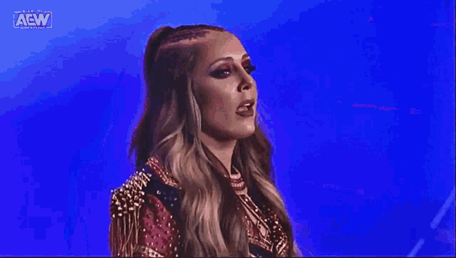 a woman in a red and gold outfit is standing in front of a blue background on a stage .