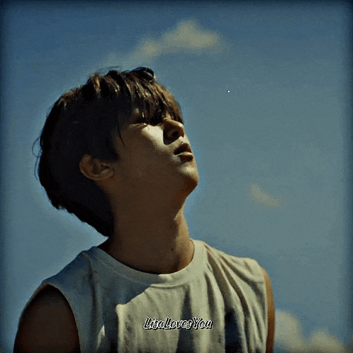 a young man wearing a white tank top that says lisa loves you looks up at the sky