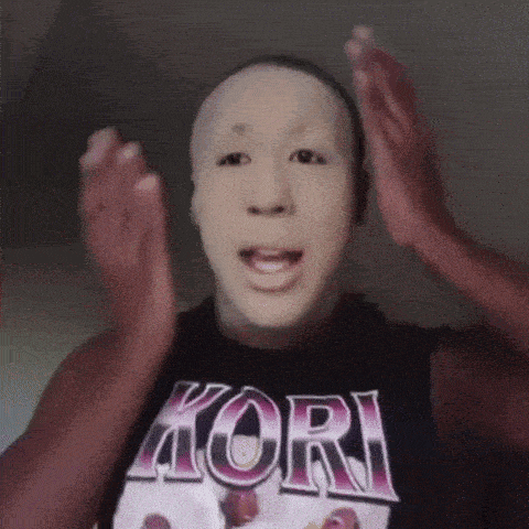a man wearing a mask and a kori shirt is clapping his hands