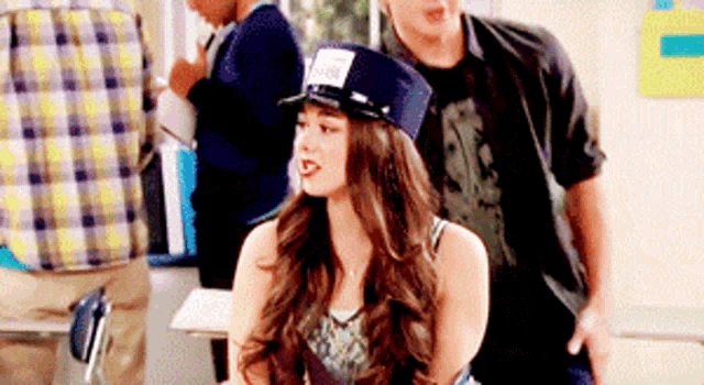 a girl wearing a police hat is sitting in a classroom next to a man