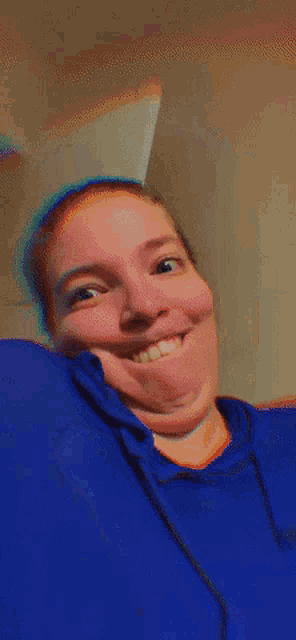 a woman wearing a blue shirt is smiling and looking at the camera