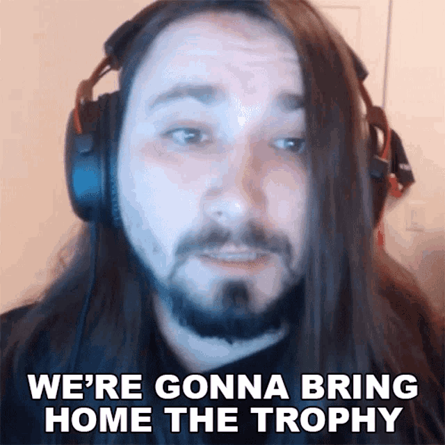 a man with long hair and a beard is wearing headphones and saying we 're gonna bring home the trophy