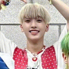 a young man with blonde hair is smiling and wearing a red and white polka dot shirt and necklace .