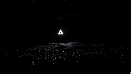 a crowd of people watching a concert with a large screen behind them that says ' a '