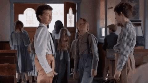 a group of children are standing in a hallway talking to each other in a church .