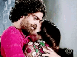a man in a pink shirt is kissing a woman on the cheek