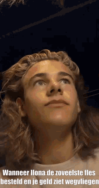 a young man with long hair is looking up at something