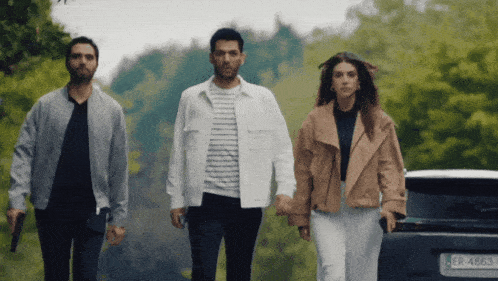 three people walking in front of a car with a license plate that says er4863