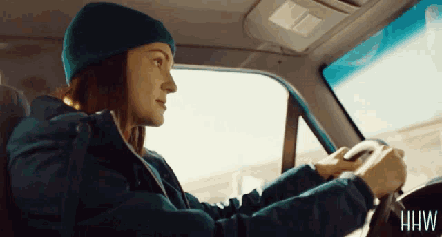a woman is driving a car with the letters hw on the bottom