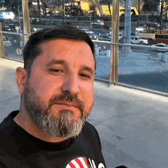 a man with a beard is wearing a black t-shirt that says ' u.s. ' on it
