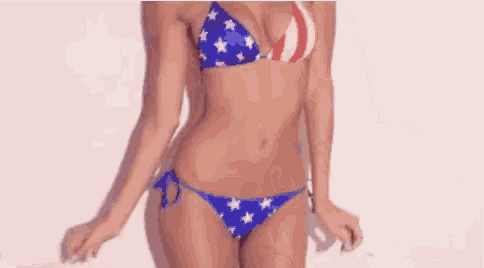 a woman in a bikini is dancing in front of a white wall .