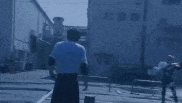 a man in a white t-shirt is standing next to a car with blood coming out of it .