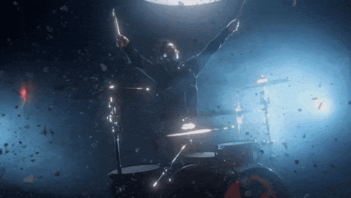 a man is playing drums in a dark room with confetti falling around him