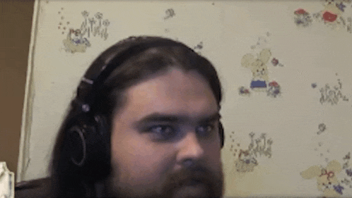 a man with a beard wearing headphones in front of a white board