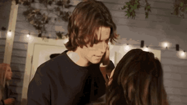 a man is touching a woman 's face while they are standing next to each other .