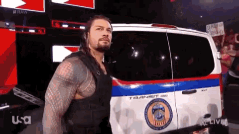 a man in a black vest is standing in front of a transit van .