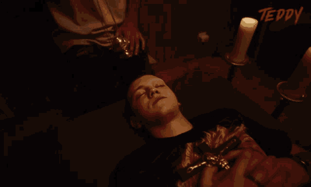 a man laying on a bed with candles and the word teddy on the bottom right