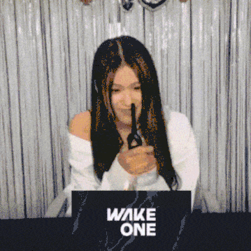 a woman is holding a pair of scissors in front of a wake one sign