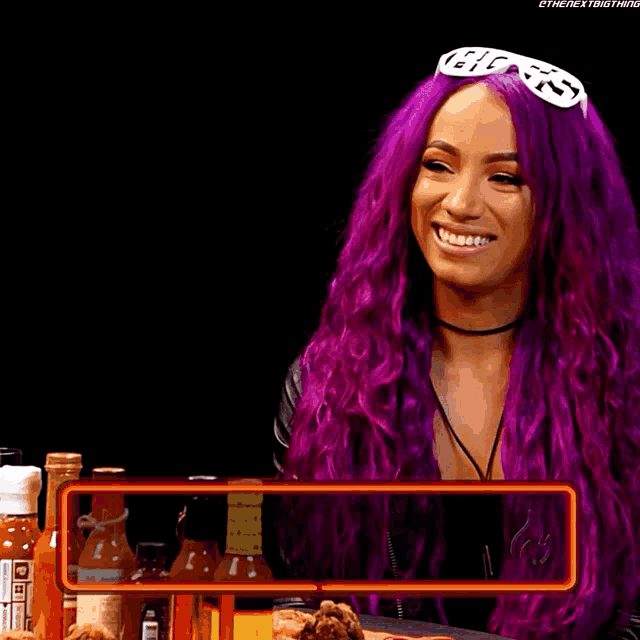 a woman with purple hair and a sign that says sasha banks on it