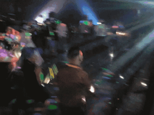 a group of people are dancing in a dark room with a blue light behind them