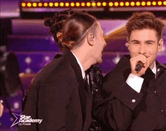 a man singing into a microphone with a star academy logo on the bottom