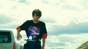 a man wearing a black t-shirt with a lightning bolt on it stands in front of a white van
