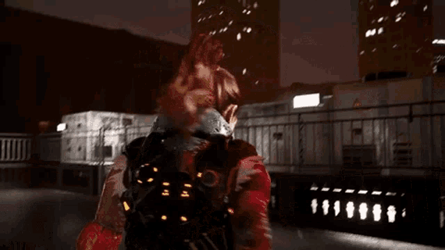a person in a red jacket is standing on a balcony at night .