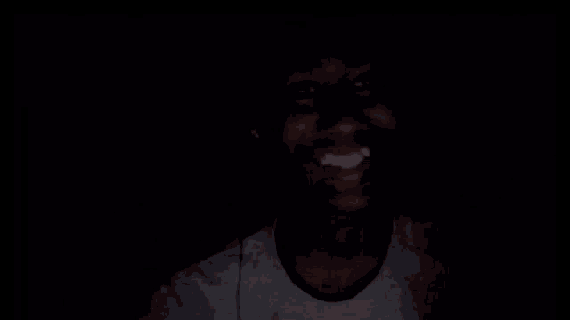 a man is making a peace sign in the dark .