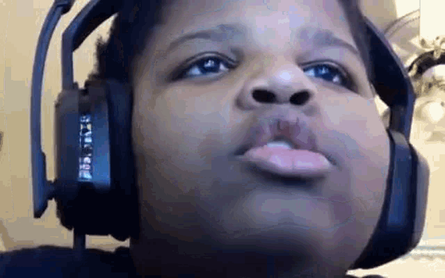 a young boy wearing headphones is blowing a kiss .