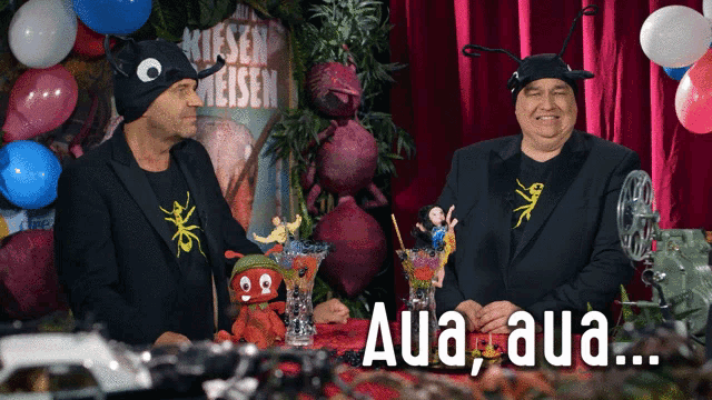 two men are standing in front of a sign that says aua